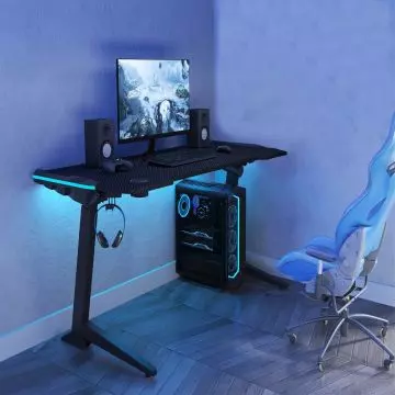 Mahmayi GET119X-L black height adjustable gaming desk with blue RGB LED lighting headphone hook and gaming PC setup in a dark room