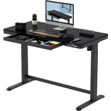Black adjustable standing desk with built-in drawer  holding computer monitor  keyboard  mouse  camera  phone  and small potted plant.