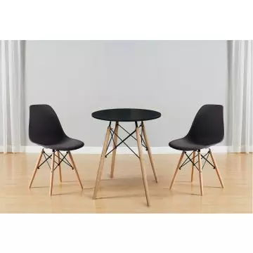 Black round dining table with beech wood quad legs paired with two black Eames style DSW chairs on light wood flooring