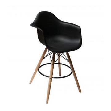 Black Eames style DAW armchair bar stool with natural wood legs and black metal footrest ring shown at an angle