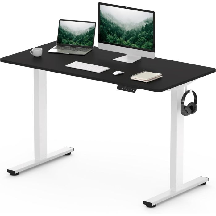 Adjustable black standing desk with white legs  featuring a computer monitor  laptop  keyboard  mouse  notebook  and headphones on a hook.